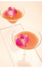 The Leblon Orchid cocktail recipe is a peach colored drink made from Leblon cachaca, Grand Marnier orange liqueur, Campari, tangerine juice and apple juice, and served shaken in a chilled cocktail glass garnished with edible orchid petals.